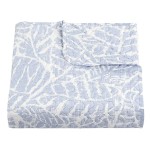 Narzuta drukowana Remo 170x210 w błękitnym kolorze, z kwiatowym wzorem na białym tle. Produkt leży na płasko, z widocznym detalem obszycia oraz kołnierzyka. Jednolity kolor tła podkreśla wzór narzuty. Idealna do aranżacji wnętrz.