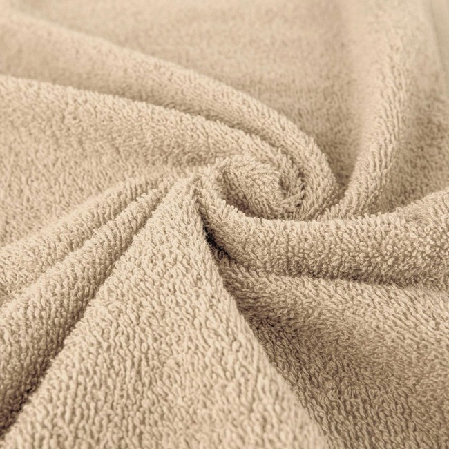 Ręcznik bawełniany 70x140 cm w kolorze kawowym, zwinięty w delikatne fałdy. Materiał o teksturowanej powierzchni, widoczny miękki splot. Tło neutralne, co podkreśla kolor i fakturę produktu.