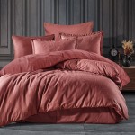 Pościel satyna bawełniana żakardowa w kolorze ceglanym, rozłożona na łóżku. Komplet zawiera poszewki na poduszki o różnych wymiarach oraz narzutę z subtelnym wzorem liści.