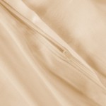 Pościel z materiału satynowego w kolorze jasnego beżu, z widocznym zamkiem błyskawicznym. Ujęcie z bliska, ukazujące gładką teksturę tkaniny. Zamek umieszczony na krawędzi, umożliwiający łatwe zakładanie poduszki.