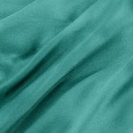 Pościel bawełniana w kolorze ciemnego turkusu, wykonana z satynowego materiału, ukazana w zbliżeniu na gładką, teksturowaną powierzchnię. Widoczne zgięcia i fałdy tkaniny, co może wskazywać na jej miękkość i elastyczność.