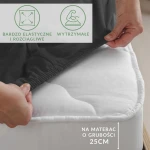 Prześcieradło jersey z elastanem w kolorze czarnym, rozłożone na materacu o grubości 25 cm. Ujęcie z boku, pokazujące elastyczny brzeg. Widoczne napisy informujące o właściwościach: bardzo elastyczne i rozciągliwe, wytrzymałe.