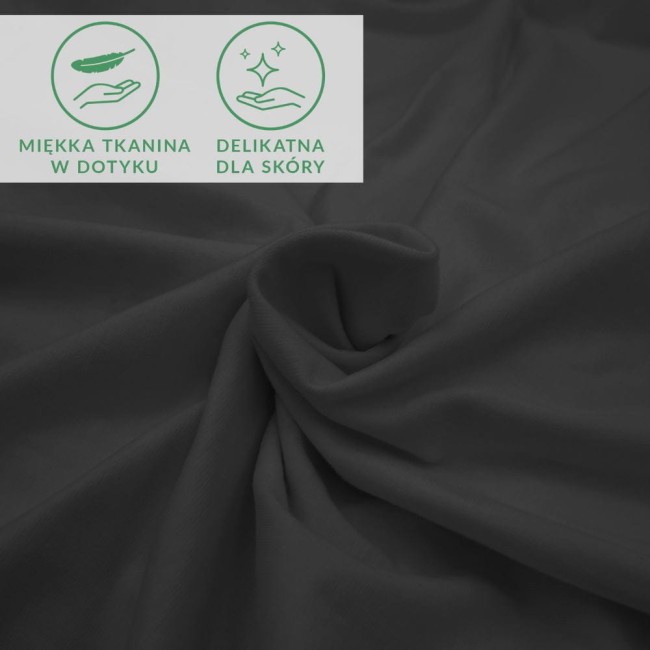 Czarne prześcieradło jersey z elastanem 200x220, leżące na gładkiej powierzchni, z delikatnie marszczonymi krawędziami, idealne do łóżek dużych rozmiarów. Widoczne ikony informujące o miękkiej tkaninie i delikatności dla skóry.