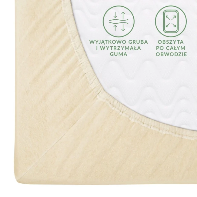Prześcieradło jersey z gumką 80x160 w kolorze kremowym, leżące na białym tle. W widocznym detalu widać elastyczną gumkę, która obszernie wykończona jest na całym obwodzie. Na materiale są czytelne napisy informujące o wytrzymałości gumy.