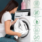 Prześcieradło jersey z gumką 140x200 w kolorze białym, rozłożone na miękkiej powierzchni. W tle widoczna pralka, na której stoją bidony z detergentami.