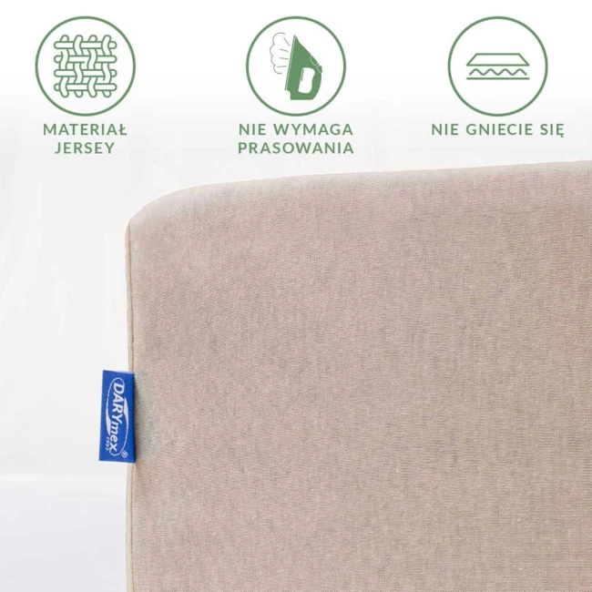 Prześcieradło jersey z gumką 180x200 w kolorze beżowym, leżące na białym tle. Zbliżenie na gładką fakturę materiału, na którym widoczne logo DARYNEX i ikony informujące o właściwościach nie wymagających prasowania oraz odporności na zagniecenia.