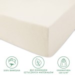 Prześcieradło jersey z gumką w kolorze ecru, wykonane z 100% bawełny. Na zdjęciu widoczny bok prześcieradła z delikatną, gładką teksturą. Produkt rozłożony, idealnie dopasowany na materacu, z czytelnymi informacjami o materiałach i gramaturze.
