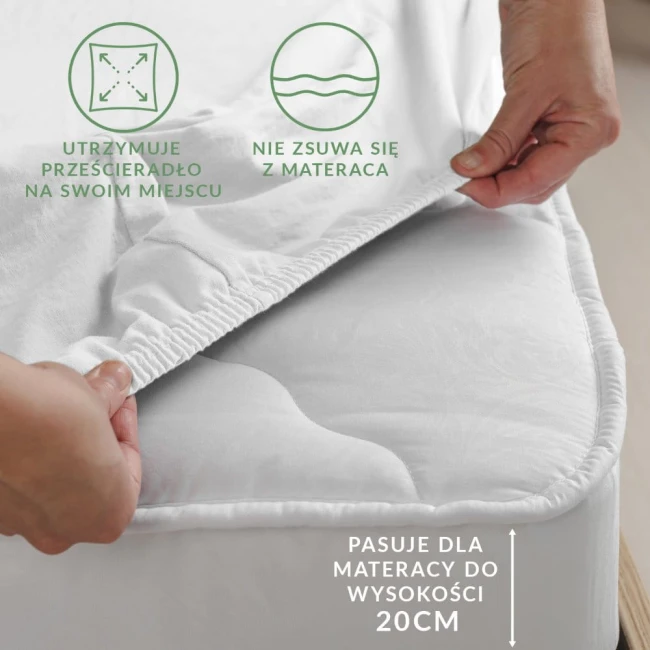 Prześcieradło jersey z gumką w kolorze jasnego turkusu, ukazane w zbliżeniu na ręce, które naciągają materiał na krawędzi materaca. Widoczne są elastyczne brzegi zapobiegające zsuwaniu.