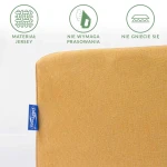 Prześcieradło jersey z gumką w kolorze musztardowym, rozłożone, widok z boku. Materiał nie wymaga prasowania, jest gładki i nie gniecie się. Z lewej widoczna metka producenta na niebieskim tle.