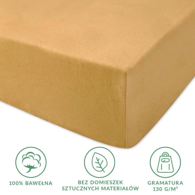Prześcieradło jersey z gumką 160x200 w kolorze musztardowym, wykonane w 100% z bawełny, widoczne z boku w leżącej pozycji. Delikatna, gładka faktura, przyjemna w dotyku. Widoczne logo oraz symbole dotyczące składu materiału.