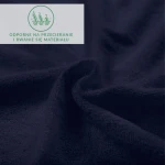 Prześcieradło frotte z gumką 90x200 w kolorze ciemnego granatu, ukazane w zbliżeniu na teksturę materiału. Zagięte i rozłożone, ukazuje miękką, odporną na przecieranie powierzchnię. W rogu widoczny napis informacyjny o właściwościach materiału.