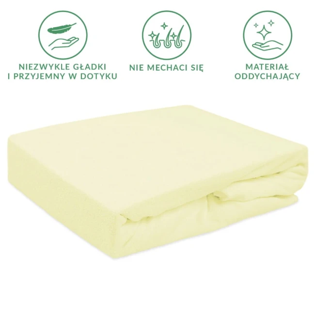 Prześcieradło frotte z gumką 90x200 w kolorze kremowym, leżące na boku, z wyraźnie widoczną fakturą materiału. Prezentuje się w prostym otoczeniu, na jednolitym tle, bez zbędnych detali. Dobrze dopasowuje się do materaca, co podkreśla jego użytkowość.