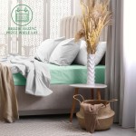 Prześcieradło frotte z gumką 120x200 w kolorze morskim, rozłożone na łóżku z szarymi poduszkami. Otoczenie to elegancka sypialnia z jasnymi zasłonami, białą podstawką i wazonem z wyschniętymi kwiatami. Tło z delikatnym wzorem.
