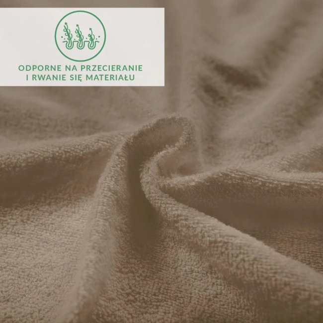 Prześcieradło frotte z gumką o wymiarach 140x200 w kolorze kakao, ukazane w zbliżeniu, na lekko pomarszczonym tle, ukazuje miękką teksturę materiału oraz jego elastyczność. Widoczne logo i informacje dotyczące odporności na przecieranie.