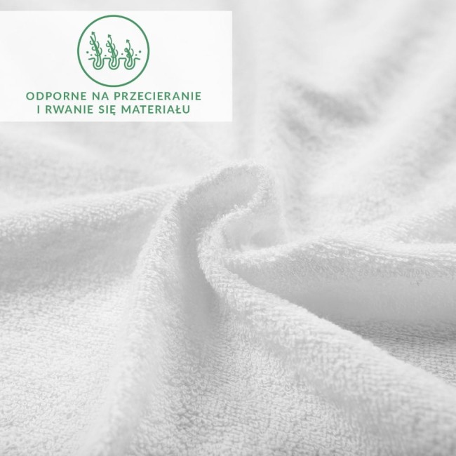 Prześcieradło frotte z gumką 160x200 w kolorze białym, leżące na płasko. Widać teksturę materiału, który jest miękki i odpowiedni do spania. Elementy tekstylne są gładkie, a tło jest neutralne. Widoczny napis reklamowy na górze zdjęcia.
