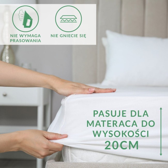 Prześcieradło frotte z gumką w kolorze jasnym róż, ukazane w zbliżeniu, naciągnięte na materac. Widoczne napisy Pasuje dla materaca do wysokości 20CM, informacje o braku konieczności prasowania oraz o odporności na gniecenie. Ułożone w sypialni.