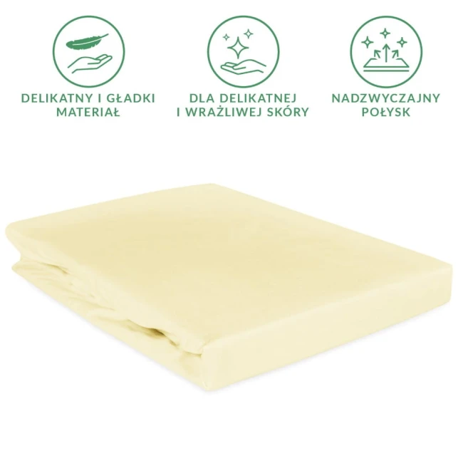 Prześcieradło satynowe z gumką 160x200 w kolorze kremowym, rozłożone składane na białym tle. Materiał wygląda gładko i błyszcząco, idealne dla delikatnej skóry. Gumka wzmocniona, zapewnia stabilność na materacu.