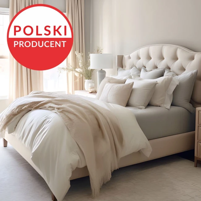 Prześcieradło jersey z elastanem w kolorze niebieskim, rozmiar 200x220, leży na łóżku, obok biała narzuta i poduszki. Tło to jasny, minimalistyczny pokój z beżowym łóżkiem i lampą. Widoczne detale tkaniny i faktura materiału.