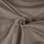 Pościel satyna bawełniana 220x200 w kolorze ciemnego beżu, lekko podniesiona, ukazuje gładką, matową teksturę tkaniny. Zbliżenie na materiał ukazuje jego miękkość i elastyczność, z brzegami naturalnie opadającymi.