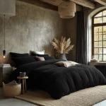 Pościel frotte 160x200 w kolorze czarnym, rozłożona na łóżku, z poszewkami w różnych odcieniach. W tle ciepłe oświetlenie, rośliny dekoracyjne, okno. Faktura materiału teksturowana; kompozycja w stylu skandynawskim.