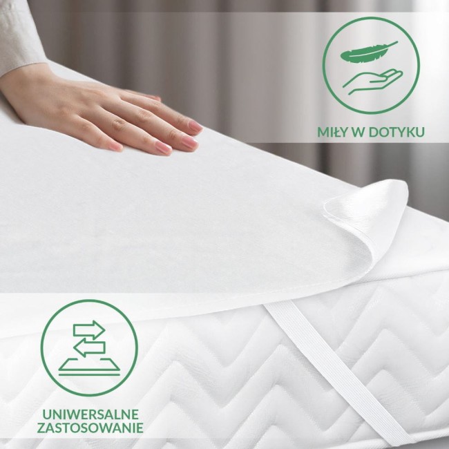 Ochraniacz na materac 160x200 cm w kolorze białym, pokazany z bliska na rozłożonym materacu. Widać gładką, teksturowaną powierzchnię, a także uchwyconą rękę na produkcie. Widoczne są elastyczne paski mocujące. Tło w neutralnych odcieniach.