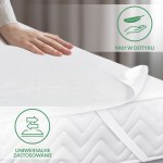 Ochraniacz na materac 180x200 w kolorze białym, leżący na materacu. Zbliżenie na gładką, teksturowaną powierzchnię. Widoczna dłoń dotykająca materiału, który sprawia wrażenie miękkiego w dotyku. Elementy mocujące na bokach. Tło w odcieniu szaro-białym.