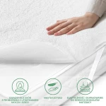 Ochraniacz na materac 70x140 cm w kolorze białym, wykonany z miękkiego materiału, ukazany z boku. Na zdjęciu widoczne ręka dotykająca powierzchni ochraniacza oraz brak widocznych napisów lub wzorów.