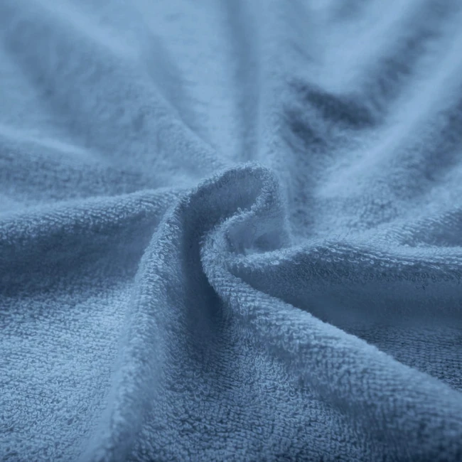 Pościel frotte 160x200 w kolorze błękitnym, z miękką, teksturowaną powierzchnią. Ułożona w rozciągniętej pozycji, z wyraźnie widoczną fakturą materiału. Tło proste, co podkreśla kolor i jakość tkaniny.