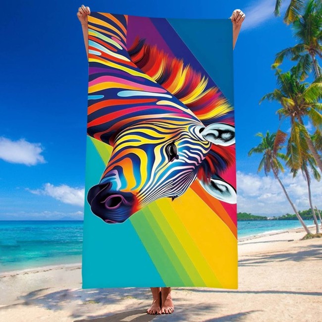 Ręcznik plażowy 100x180 cm z kolorowym wzorem zebry, wykonany z szybkoschnącej mikrofibry. Produkt trzymany na plaży, w pełnym kadrze, z tłem w postaci morza i palm. Widoczne intensywne kolory i szczegóły wzoru, z lekko matowym wykończeniem.