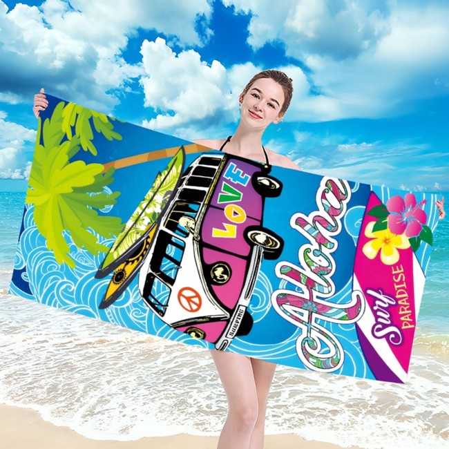 Ręcznik plażowy 100x180 cm Aloha Love, szybkoschnący z mikrofibry, w kolorze niebieskim z grafiką furgonetki, palm i hasła Aloha Love, leżący na plaży, trzymany przez osobę w stroju kąpielowym. Widoczna tekstura materiału i wzór.