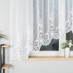 Firana gotowa BERENIKA żakardowa, o wymiarach 400x160 cm, w kolorze białym. Zawieszona na oknie, z haftowanym wzorem na dolnej krawędzi. Tło neutralne, z wazonem oraz rośliną w pobliżu. Przez firanę prześwituje światło, nadając przytulności wnętrzu.