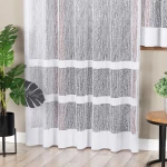Firana gotowa WIKTORIA w kolorze białym, wykonana z żakardowego materiału, o wymiarach 200x250 cm. Fotografia przedstawia firanę wiszącą na karniszu, z delikatnym wzorem w postaci gałęzi. W tle widoczne rośliny doniczkowe i stół, na jasnej podłodze.