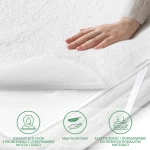 Ochraniacz na materac 200x200 Robson w kolorze białym, z miękką, teksturowaną powierzchnią. Widoczna ręka dotykająca materiału. Produkt elastyczny, dopasowujący się do różnych rodzajów materacy, idealny dla osób z problemami z utrzymaniem moczu.