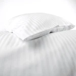 Pościel hotelowa bawełniana 160x200 w pasy 1 cm, biała, z zakładką 30 cm. Widok z góry, pokazujący złożone poszewki na poduszki na gładkim tle. Materiał o gładkiej fakturze, z subtelnym wzorem pasków, bez widocznych napisów czy logo.