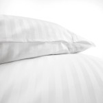 Pościel hotelowa bawełniana 220x200 w białe pasy 2-cm, z zakładką 30 cm. Widok z dołu na poszwę i poduszki, ułożone blisko siebie na gładkim tle. Materiał gładki, z delikatnym wzorem pasków, idealny do eleganckiej aranżacji sypialni.