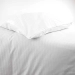 Poszewka na poduszkę hotelową 50x60 cm, biała w delikatne paski 4 mm, leżąca na gładkim tle. Ujęcie z boku, pokazujące zakładkę. Materiał gładki, bez widocznych napisów. Idealna dla aranżacji sypialni w stylu klasycznym.