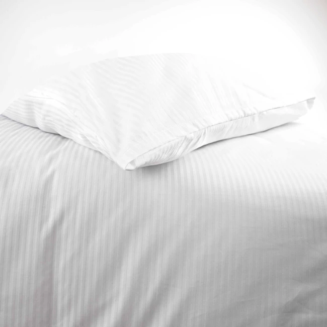 Poszewka na poduszkę hotelową 50x60 cm, biała w delikatne paski 4 mm, leżąca na gładkim tle. Ujęcie z boku, pokazujące zakładkę. Materiał gładki, bez widocznych napisów. Idealna dla aranżacji sypialni w stylu klasycznym.
