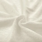 Poszewka frotte 80x80 w kolorze ecru, wykonana z miękkiego materiału o teksturze pętelkowej. Produkt leży na płasko, ukazując jego delikatną strukturę i neutralny odcień. Idealna do dekoracji poduszek w sypialni lub salonie.