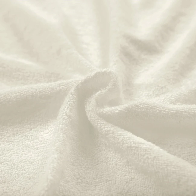 Poszewka frotte 80x80 w kolorze ecru, wykonana z miękkiego materiału o teksturze pętelkowej. Produkt leży na płasko, ukazując jego delikatną strukturę i neutralny odcień. Idealna do dekoracji poduszek w sypialni lub salonie.