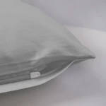 Poszewka satynowa 70x80 w kolorze popielatym, leżąca na jasnym tle. Widoczny delikatny połysk materiału, z zamkiem błyskawicznym u dołu. Brak dodatkowych wzorów lub napisów.