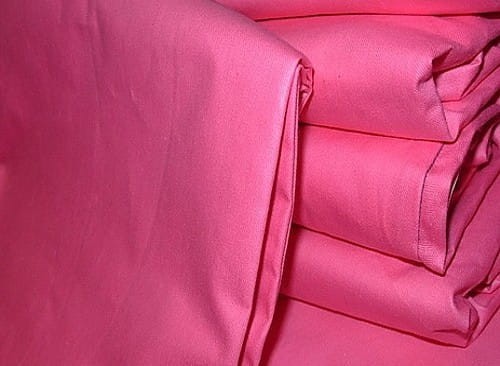 Poszwa wsypowa w kolorze różowym, rozłożona i zwinięta w kilka warstw, wykonana z gładkiego materiału. Brak widocznych wzorów i napisów. Zdjęcie na jednolitym tle, co podkreśla intensywność koloru. Rozmiar: 200x220 cm.